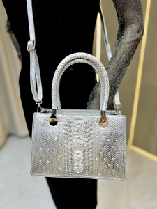 Detail of silver snake-pattern handbag with luxury crystal flowers and woven handle
