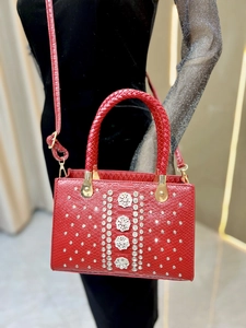 Detailed shot of red crocodile embossed leather bag with sparkling rhinestone flowers