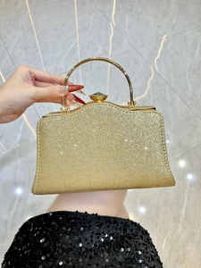 Dettaglio della pochette da sera con paillettes dorate e manico in metallo con gemma