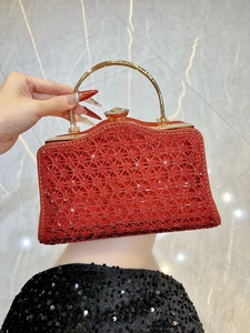 Dettaglio della borsa da sera rossa con paillettes, manico dorato e chiusura in cristallo