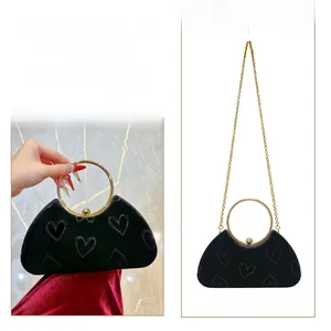Détail du sac en velours noir gaufré cœur avec poignée anneau dorée et bandoulière