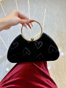 Détail d'une pochette en velours noir à cœurs avec poignée ronde dorée et fermoir