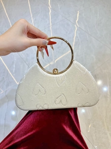 Détail du sac de soirée en velours blanc avec motifs de cœurs et poignée anneau dorée