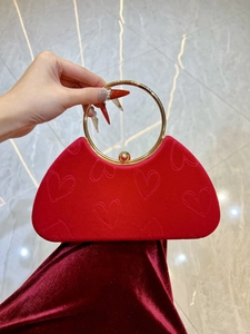 Détail du sac de soirée en velours rouge à texture cœur avec poignée dorée ronde