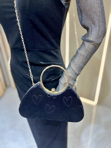 Détail d'un sac de soirée en velours noir avec flocage cœur et poignée anneau doré