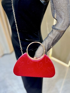 Détail du sac à main en velours rouge avec gaufrage cœur et poignée en métal doré