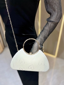 Détail d'un sac blanc gaufré de cœurs avec poignée dorée et fine bandoulière