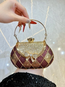 Macro detail of wine red evening bag featuring gold grid and sparkling rhinestone bow clasp