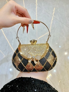 Detailed close-up of a luxury black evening clutch featuring rhinestone bow and gold ring handle