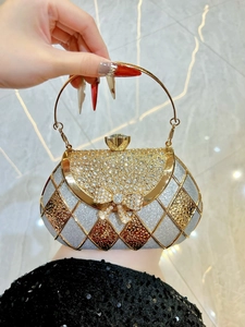 Detail of glitter evening clutch featuring a rhinestone bow and gold circular handle