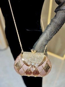 Detail of glitter evening clutch with golden grid overlay and rhinestone bow buckle