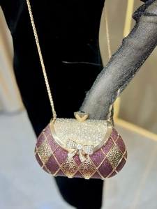 Macro detail of luxury rhinestone bow clasp and metallic magenta quilted evening clutch bag