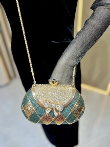 Detailed view of rhinestone bow on emerald green glitter evening clutch bag with chain
