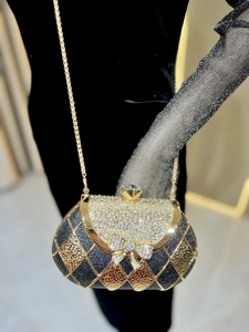 Detail of crystal bow clasp on glittering diamond evening bag with chain strap