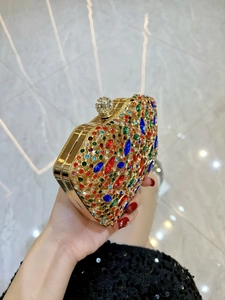 Luxurious evening clutch bag with colorful rhinestones and gold metal frame being held