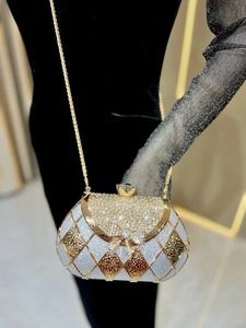 Detail of rhinestone bow clasp on luxury quilted dinner bag with chain strap