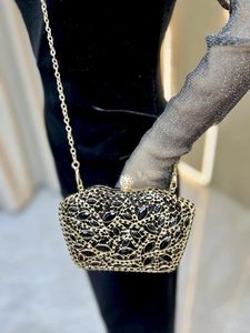 Detail of elegant black evening clutch bag with sparkling crystals and gold chain