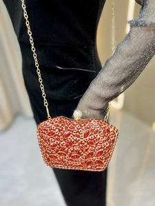 Close-up of red rhinestone floral clutch bag with gold chain and luxury crystal ball clasp