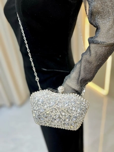 Close-up of silver evening bag with sparkling crystal floral patterns and metal chain