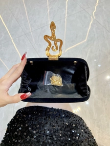 Black velvet evening clutch bag featuring a gold snake clasp and detachable chain strap