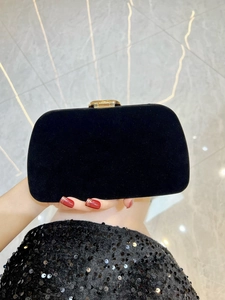 Detail of black velvet clutch bag featuring luxury snake shape clasp with sparkling rhinestones