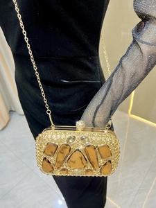 Detail of a luxury gold evening clutch bag with large amber gems and a chain strap