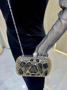 Detailed close-up of a luxury black crystal clutch bag with a sparkling spherical diamond clasp