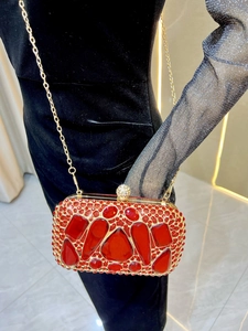 Detail of red rhinestone evening clutch with large crystals and gold chain strap