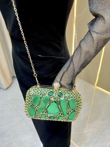 Detailed macro view of emerald crystal evening clutch bag with luxury gold chain and gems