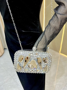 Detail of silver evening clutch with glass diamonds and metallic chain on black velvet dress