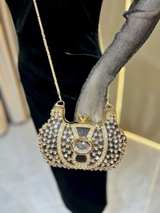 Détail d'une pochette de soirée dorée ornée de strass et d'une pierre centrale