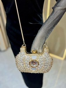 Gros plan d'une pochette de soirée en strass avec un grand cristal et une chaîne dorée