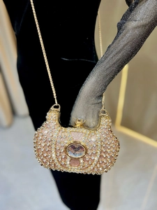 Mannequin portant un sac de soirée doré orné de strass avec une fine chaîne métallique