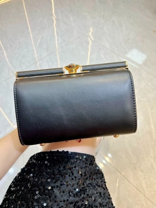Close-up of black evening bag with gold metal frame and gem-shaped clasp detailing