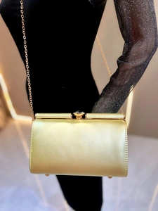 Close-up of champagne gold satin evening clutch with rhinestone buckle and chain strap