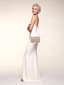 Chic light pink evening clutch bag with gold chain strap worn over white dress