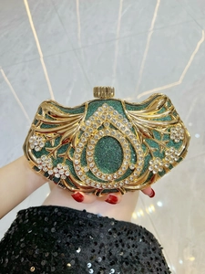 Close-up of emerald green clutch with intricate crystal scroll patterns and gold frame
