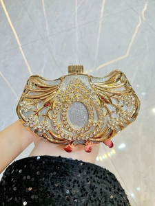 Close-up of luxury evening clutch bag with gold hollow floral pattern and sparkling crystals