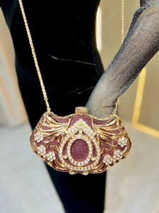 Detail of luxury evening clutch featuring gold hollow metal patterns and white rhinestones