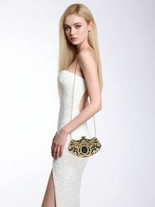 Detail of luxury rhinestone evening bag with gold chain worn by a model in a white dress