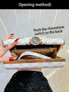 Dettaglio della pochette bianca con cuori in rilievo, chiusura a cristallo e interno a righe