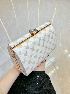 Clutch rigida bianca con cuori in rilievo e chiusura in cristallo dorato tenuta in mano