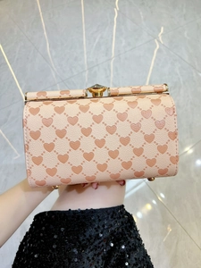 Dettaglio di borsa a mano rosa con cuori a rilievo, chiusura a cristallo e telaio oro