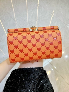Dettaglio borsa rigida arancione a cuori con chiusura dorata e texture in pelle