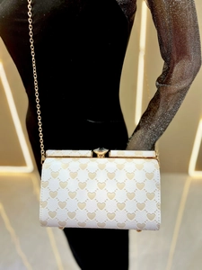 Dettaglio borsa in pelle bianca con goffratura a cuore e tracolla a catena oro