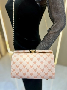 Dettaglio borsa rosa con stampa a cuori, chiusura con gemma e tracolla a catena oro