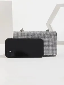 Detailed size comparison of a silver rhinestone clutch bag next to a smartphone