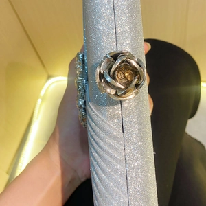 Détail d'une pochette argentée scintillante avec boucle rose et détails en strass