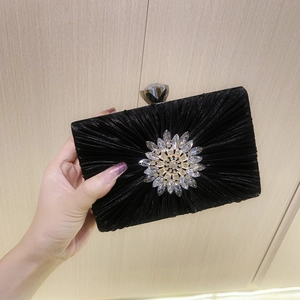 Detail of black pleated evening clutch with crystal flower and gemstone clasp