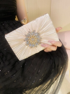 Detail of champagne pleated satin evening clutch with sunburst rhinestone ornament